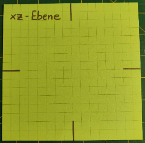 3. Zeichne auf einem Quadrat vier Linien (2 cm lang) wie in der Abbildung ein und schneide mit einer Schere entlang der Linien. Beschrifte das Blatt oben links mit xz - Ebene.