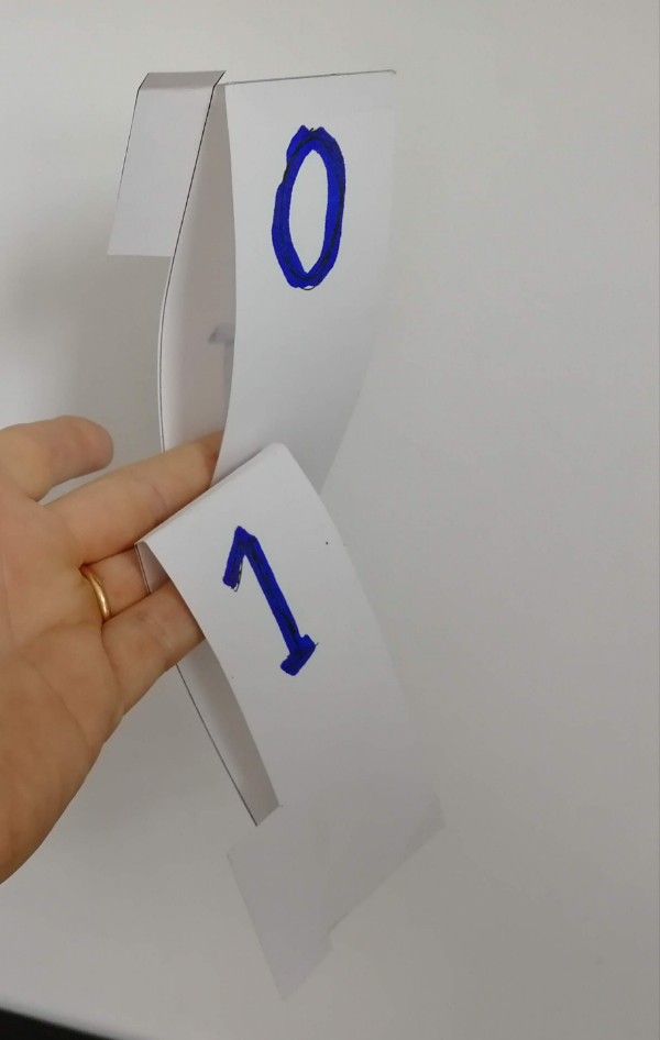 Une simple languette de carton, repliée et collée, échancrée du côté du 1 pour propager la retenue, à enfiler sur une réglette.