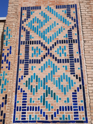 The names of Allah (up) and Muhammad (down) in square kufic on a decorated wall
